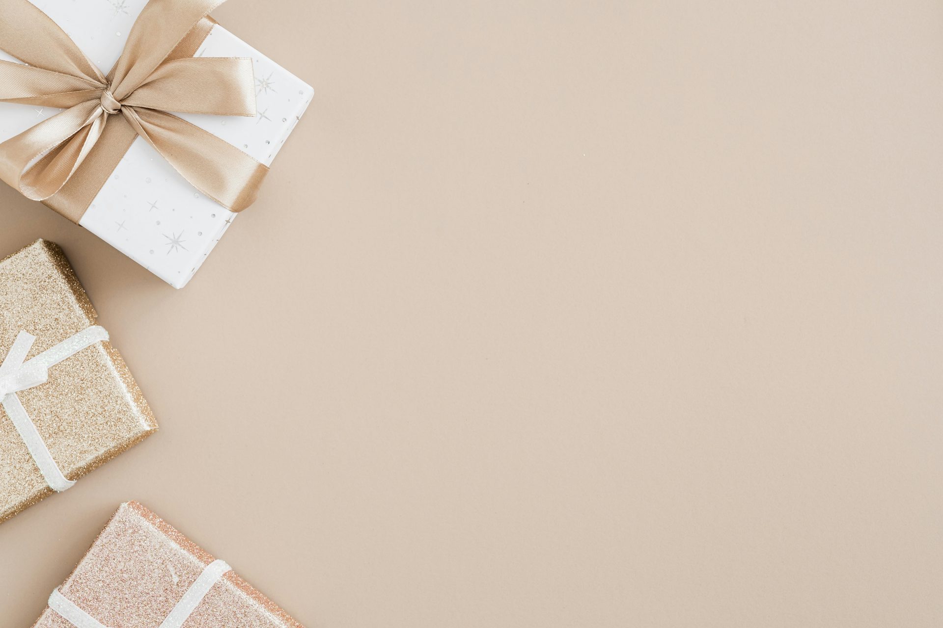 High-angle view of gift boxes with ribbons on a beige background, elegant and minimal style.
